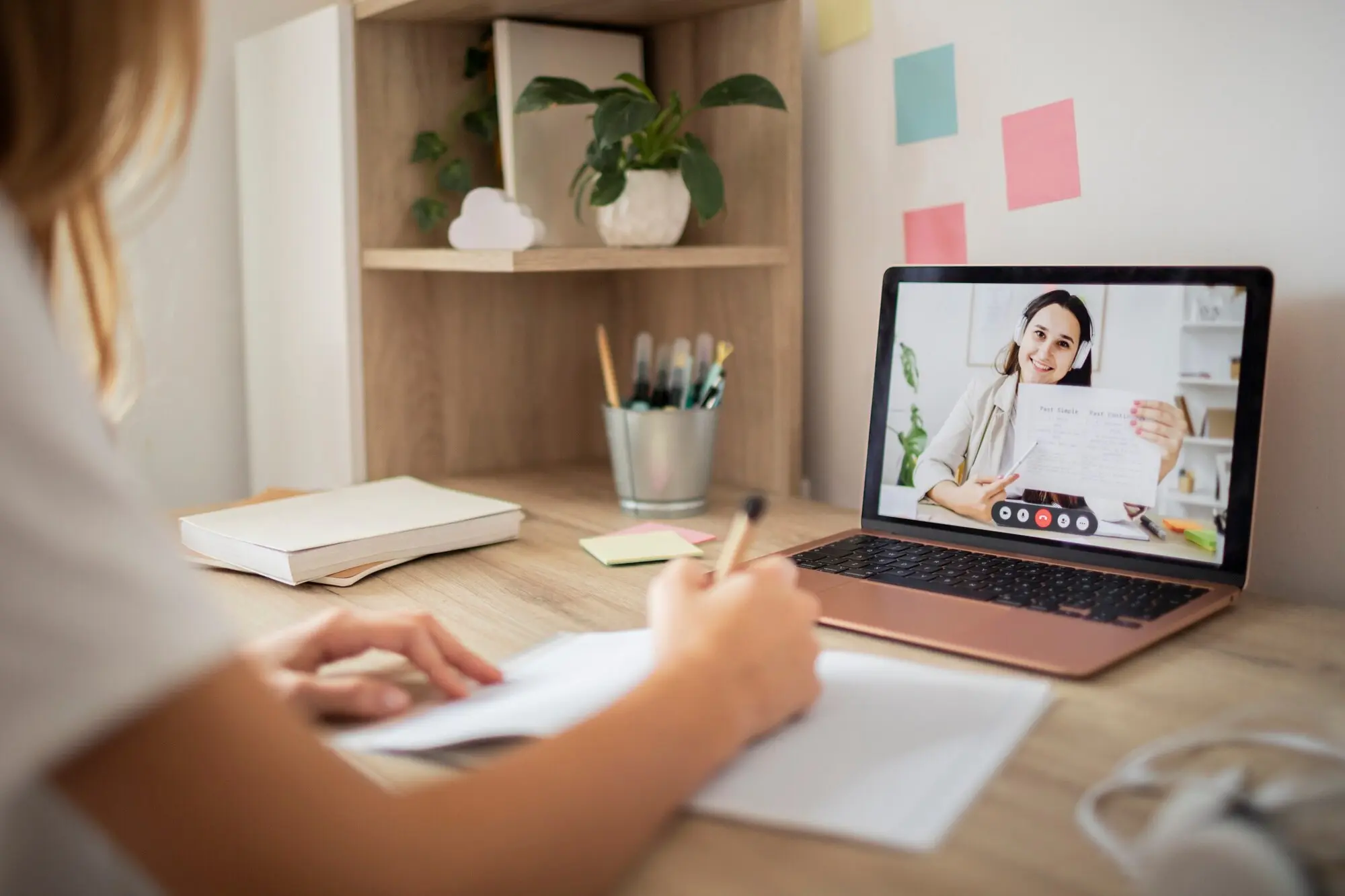 Aluna participando de aula online no notebook com anotações